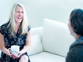 Tanya Mark holding a coffee cup while having a one-to-one coaching session with a client.
